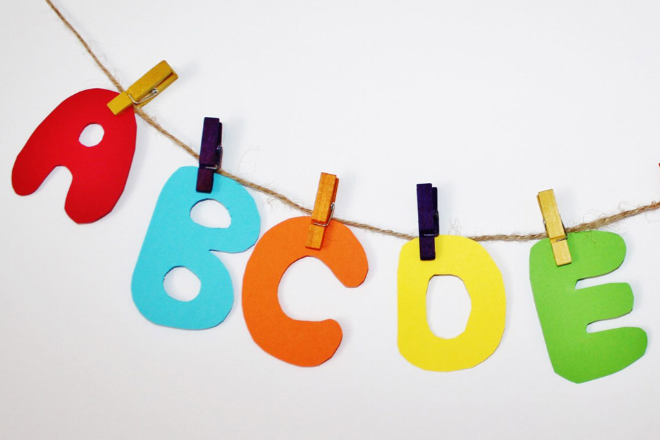 A banner made up of the letters A, B, C, D, E (different colors) clothespinned to a string.